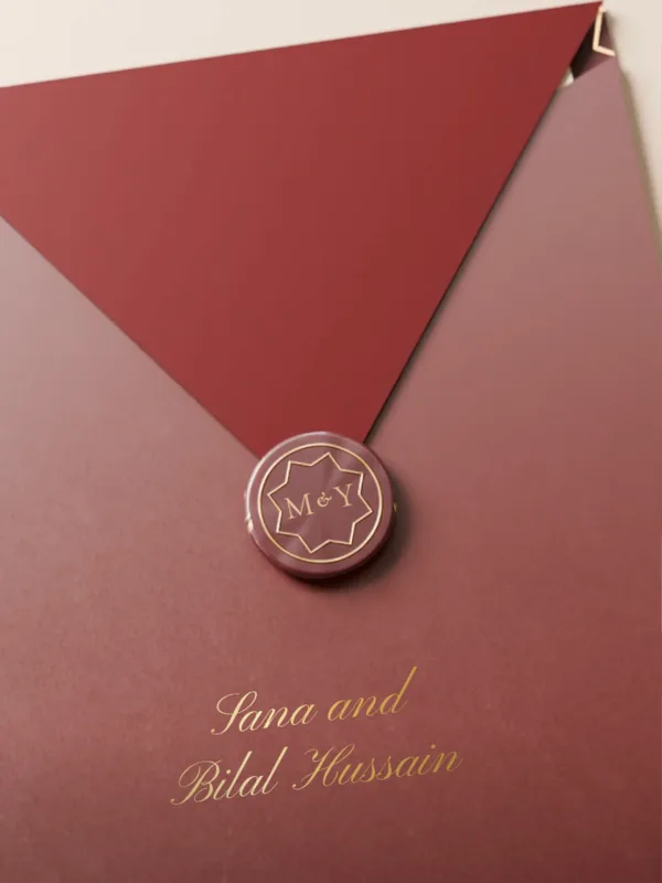 A burgundy envelope, “Sana and Bilal Hussain” written below the seal